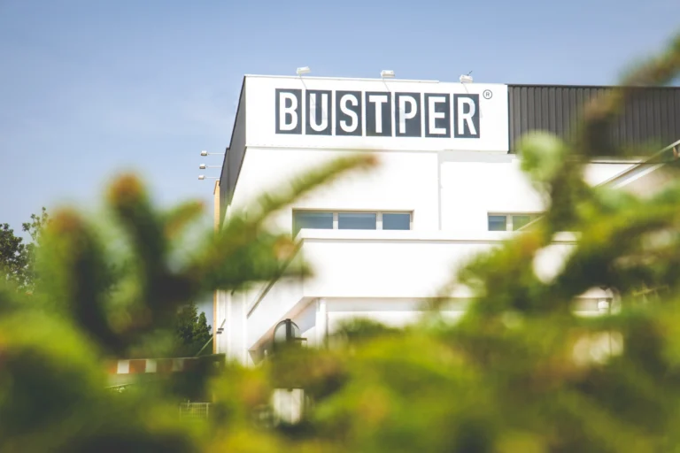 Fachada de las oficinas de Bustper a través de unas ramas